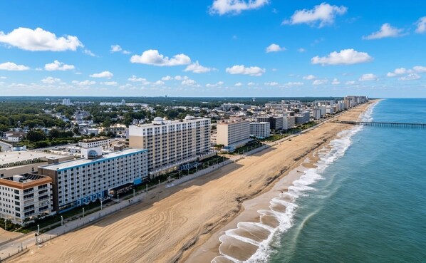 Un hotel frente al mar con varios pisos, un paseo marítimo y un muelle que se adentra en el océano.