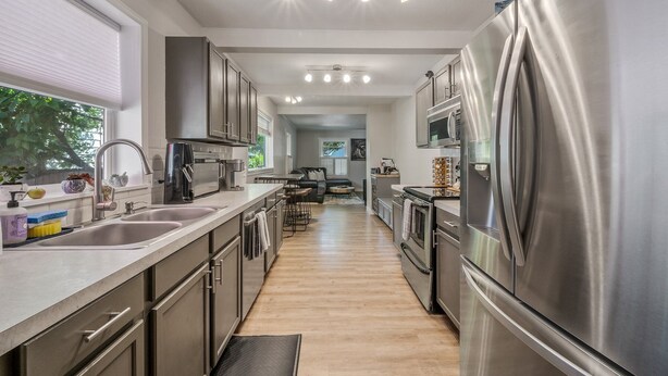 A modern kitchen with stainless steel appliances, a long countertop, and a view to a dining area. - Cozy historic downtown CDA home w/ office space. Pet friendly!  (Coeur d'Alene)
