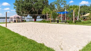 Una cancha de voleibol de playa con una red, rodeada de arena y césped.
