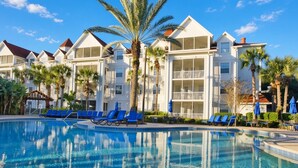 A hotel with a swimming pool, palm trees, and a clear blue sky. - Orlando | Couples Lake Retreat | Pool + Hot Tub (Orlando)