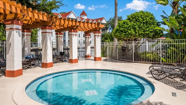 Una piscina circular con sillas de descanso y una zona de estar cubierta con techo rojo.
