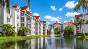 A waterfront hotel with multiple-story buildings, a central fountain, and lush greenery. - Orlando | Couples Lake Retreat | Pool + Hot Tub (Orlando)
