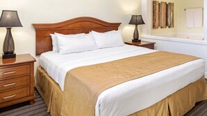 A hotel room with a large bed, two bedside tables, a wooden headboard, and a striped carpet. - Orlando | Couples Lake Retreat | Pool + Hot Tub (Orlando)