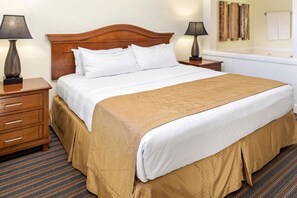 Habitación de hotel con una cama grande, dos mesitas de noche, un cabecero de madera y una alfombra a rayas.