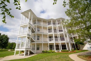 A multi-story building with balconies, a central staircase, and a well-maintained lawn.