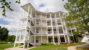 A multi-story building with balconies, a central staircase, and a well-maintained lawn. - Branson | Easy Lake Retreat | Pool + Lake (Branson)