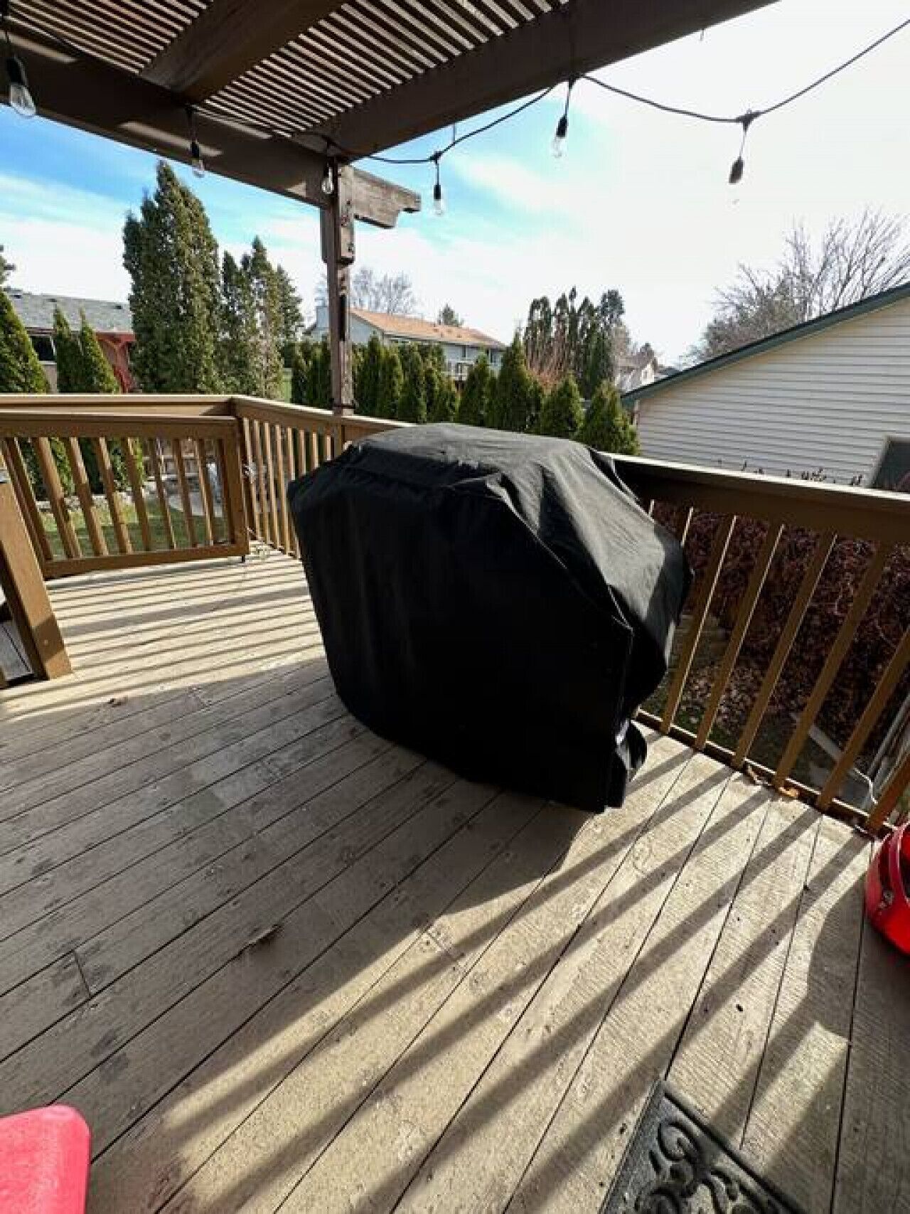 Una terrazza coperta con una griglia e luci decorative.