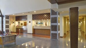 A hotel lobby with a reception desk, a red rope barrier, and a decorative column.