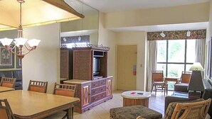 Un comedor con una mesa y sillas de madera, un televisor y un armario.
