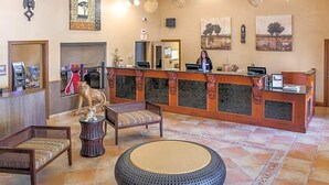 Un hall con una mesa de recepción, una silla de madera, un reposapiés redondo y una estatua de un león.