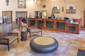 Eine Empfangshalle mit einer Rezeption, einem Holzstuhl, einem runden Hocker und einer Löwenstatue.