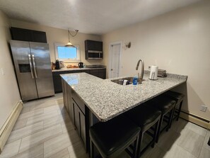 A modern kitchen with granite countertops, stainless steel appliances, and a central island with bar stools.