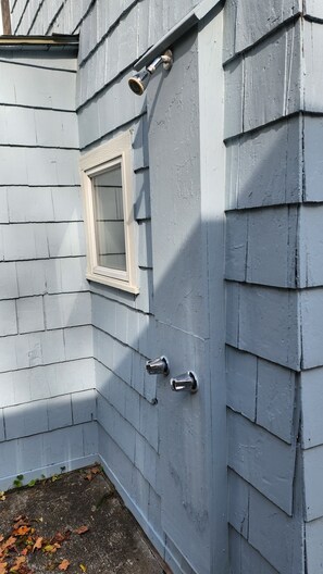 A corner of a building with a white-framed window and a door with two metallic handles.