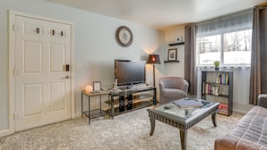 A living room with a television, a bookshelf, a lamp, and a couch. - Cozy Wasilla Apartment ~ 2 Mi to Downtown! (Wasilla)