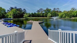 A wooden dock extending over a calm lake, surrounded by lush greenery and trees.