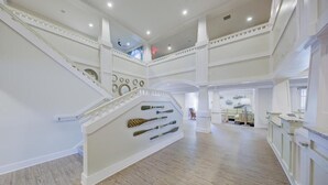 A spacious interior with a grand staircase, multiple levels, and a central seating area with a view of the upper floor.