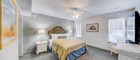 A bedroom with a bed, bedside tables, a ceiling fan, and a desk with a chair.