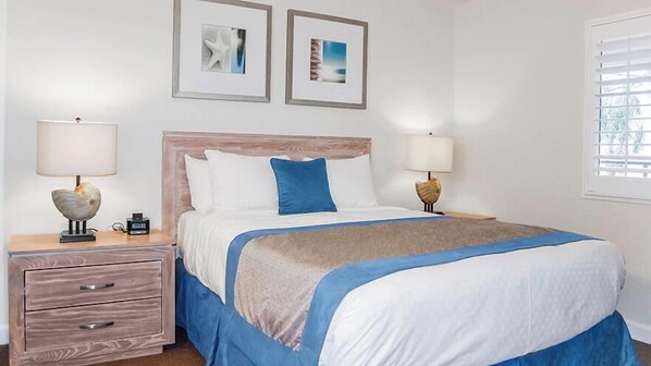 A neatly arranged bedroom with a bed, two bedside tables, and framed pictures on the wall.