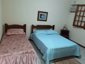 Two beds with wooden headboards, a bedside table, and a framed picture adorn this cozy space.