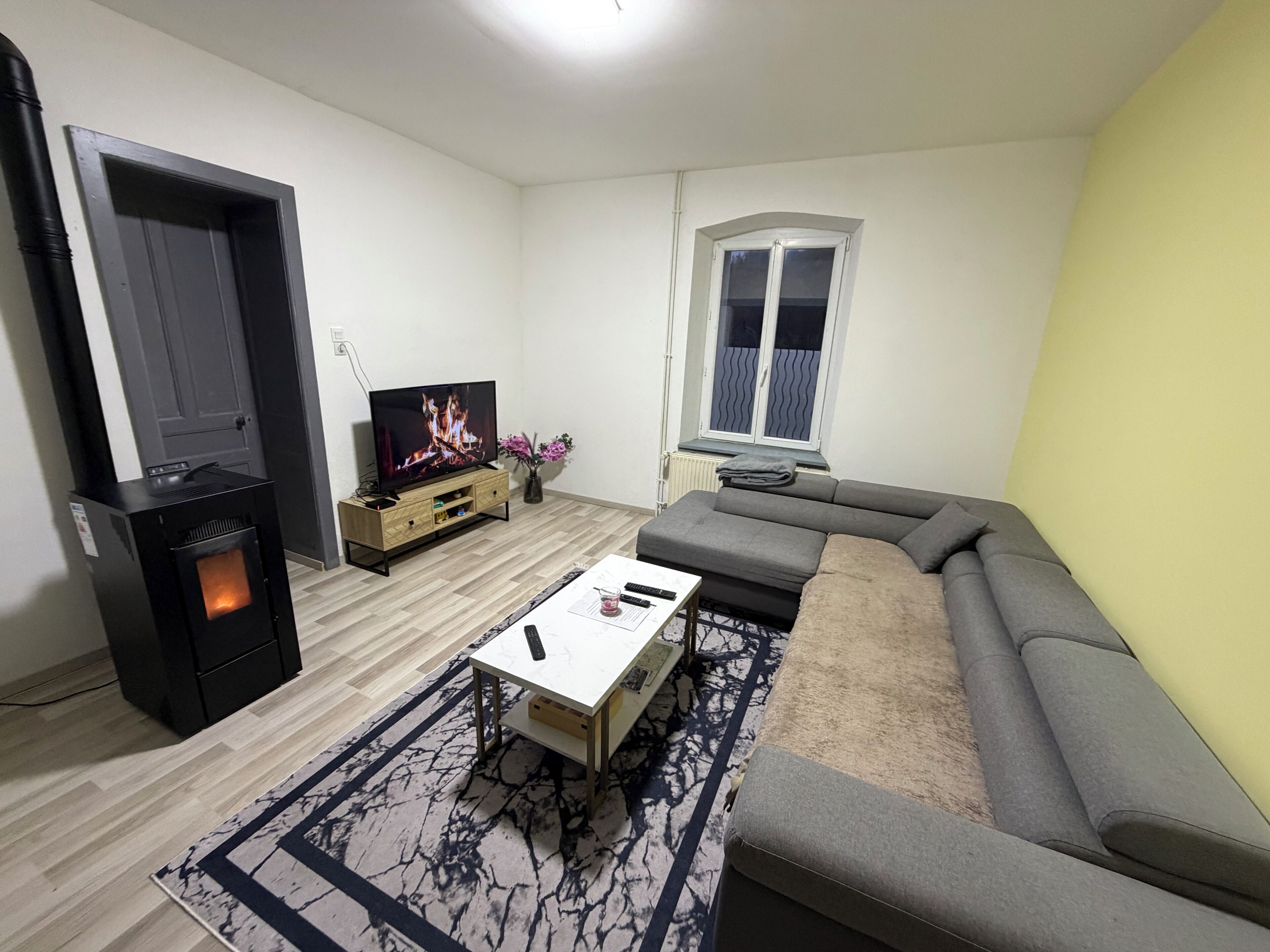 Una sala de estar con chimenea, un sofá, un televisor y una ventana.