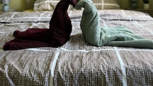 A bed with a patterned bedspread and two towels shaped like animals. - Can Appart 1 à 8 Pers (Granges-Aumontzey)
