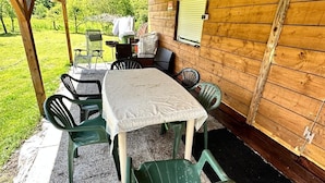A covered outdoor patio with a table and chairs, a clothesline, and a view of the surrounding greenery. - Can Appart 1 à 8 Pers (Granges-Aumontzey)