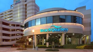 Un hôtel moderne à la façade incurvée, doté de plusieurs étages et d’une enseigne bien visible indiquant « Beach Quarters Resort Hotel ».