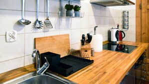 A modern kitchen with wooden countertops, stainless steel appliances, and a variety of utensils hanging on the wall. - Bonerowska 3/48 (Kraków)