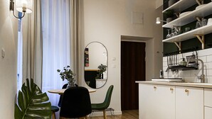 A modern kitchen with white cabinets, a wooden dining table, and a green chair. - Apartment for 4 guests, Wawel & Old Town Krakow II, św. Gertrudy (Kraków)