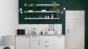 A modern kitchen with white cabinets, a microwave, a coffee maker, and shelves with plants and kitchenware. - Apartment for couples - Wawel & Old Town Krakow, św. Gertrudy (Kraków)