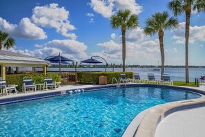 Una piscina con lettini, palme e vista sull'acqua.