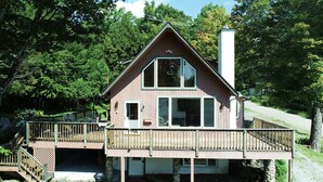 Une maison à deux étages avec un balcon, une cheminée et une terrasse.