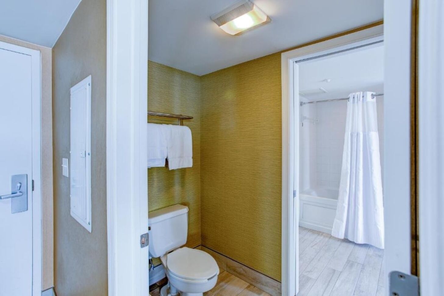 A bathroom with a toilet, a towel rack, and a shower curtain.
