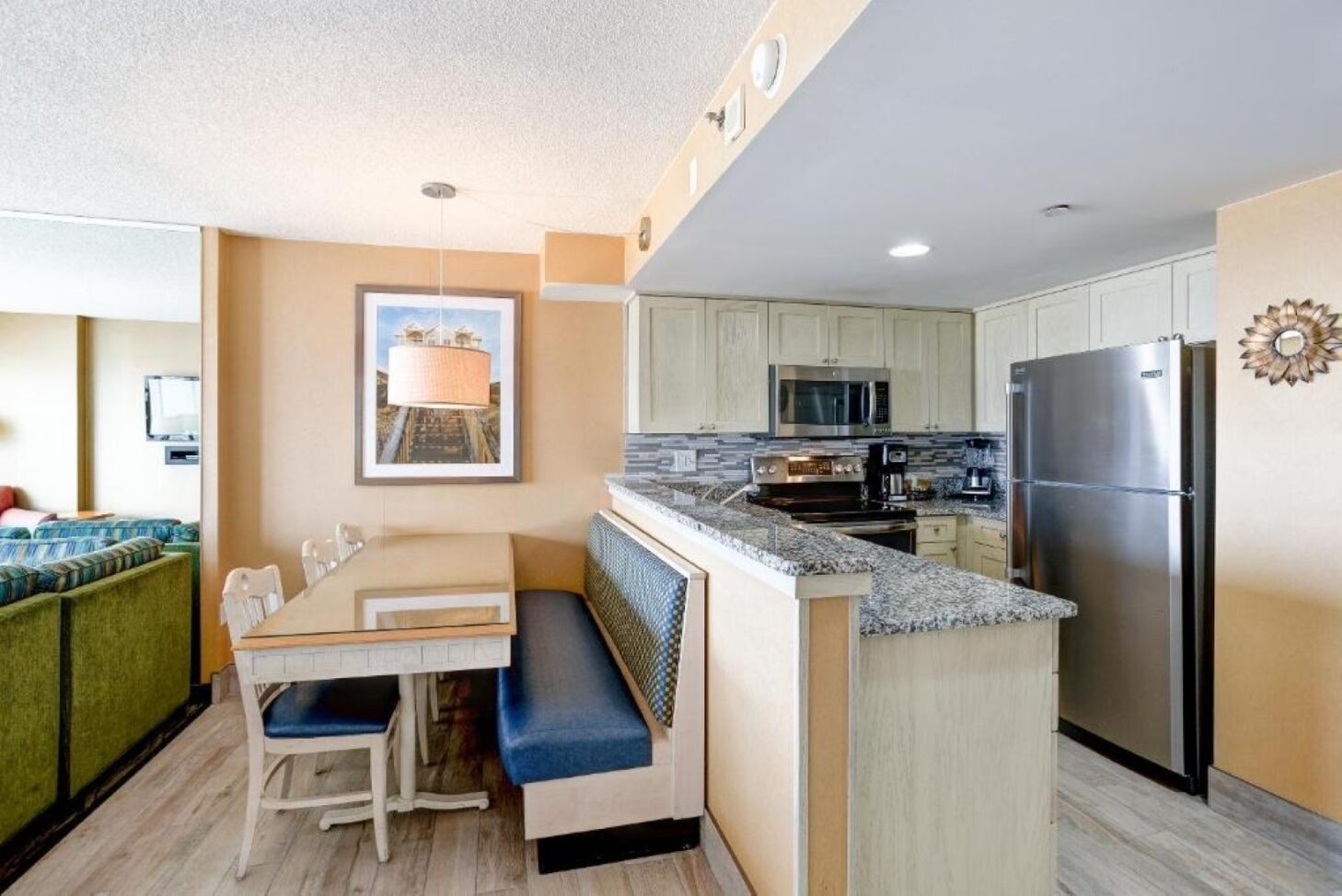 A compact kitchen with a dining area, a built-in oven, a refrigerator, and a microwave.