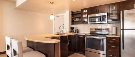 A modern kitchen with a central island, stainless steel appliances, and dark wood cabinetry.