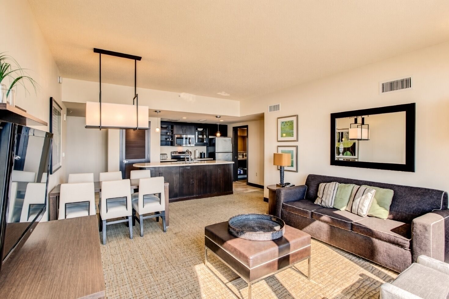 A modern living room with a sofa, chairs, a coffee table, and a kitchen area in the background.