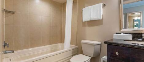 A bathroom with a bathtub, toilet, and vanity.