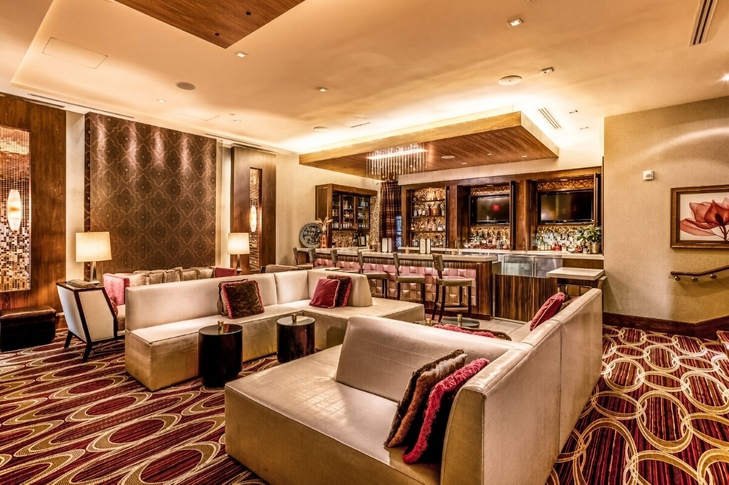 A hotel lobby with a bar area, seating arrangements, and a patterned carpet.