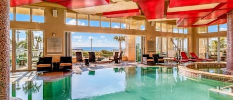 Una piscina interior con agua cristalina, rodeada de sillones de descanso y vistas al océano.