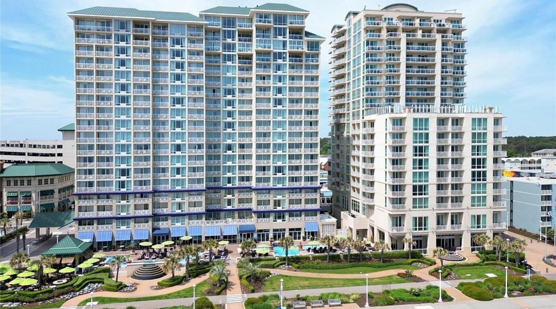 Un hôtel de grande hauteur doté de nombreux balcons, d’une piscine et d’une cour aménagée.
