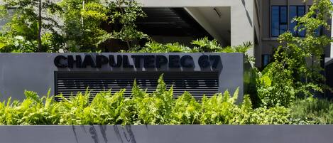 A sign for Chapultepec 67 with a modern building in the background.