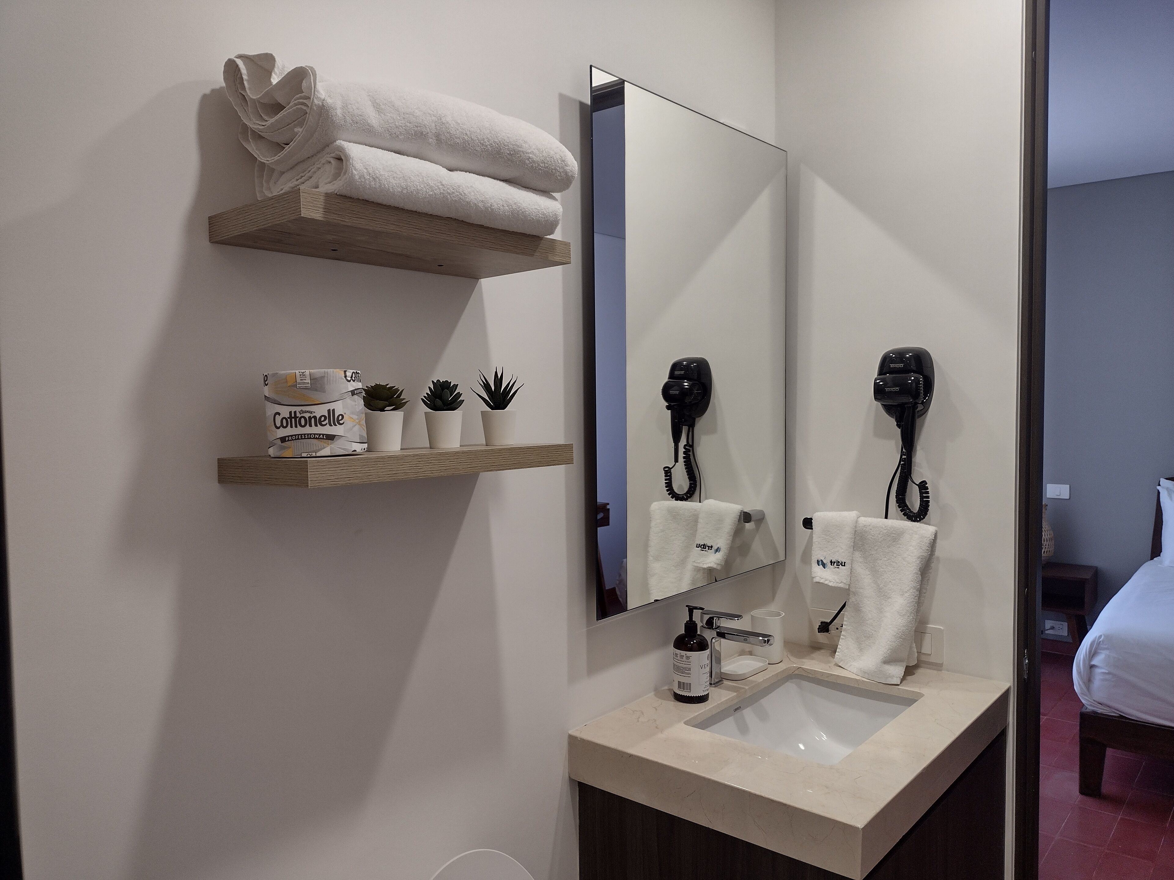 A bathroom with a sink, mirror, towel rack, and hairdryer.