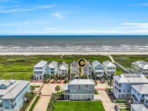 Zona residencial costera con propiedades frente a la playa, un camino central y una playa al fondo.
