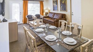 Comedor con una mesa de vidrio dispuesta para cuatro personas, rodeado de sillas estampadas.