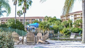 Un resort con zona de piscina, sillas de descanso y palmeras.