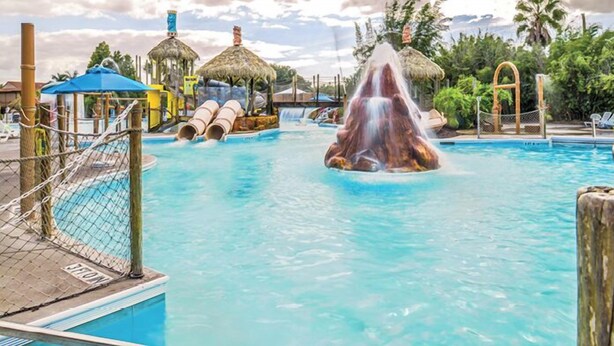 Una piscina con tobogán de agua y una formaci ón rocosa en el centro.