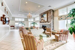 Un salon spacieux avec des fauteuils à rayures, une cheminée et une grande fenêtre.