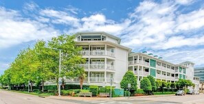 A multi-story hotel with balconies, a green lawn, and a clear blue sky. - Virginia Beach | Couples Ocean Coast Retreat | Pool + Hot Tub (Virginia Beach)