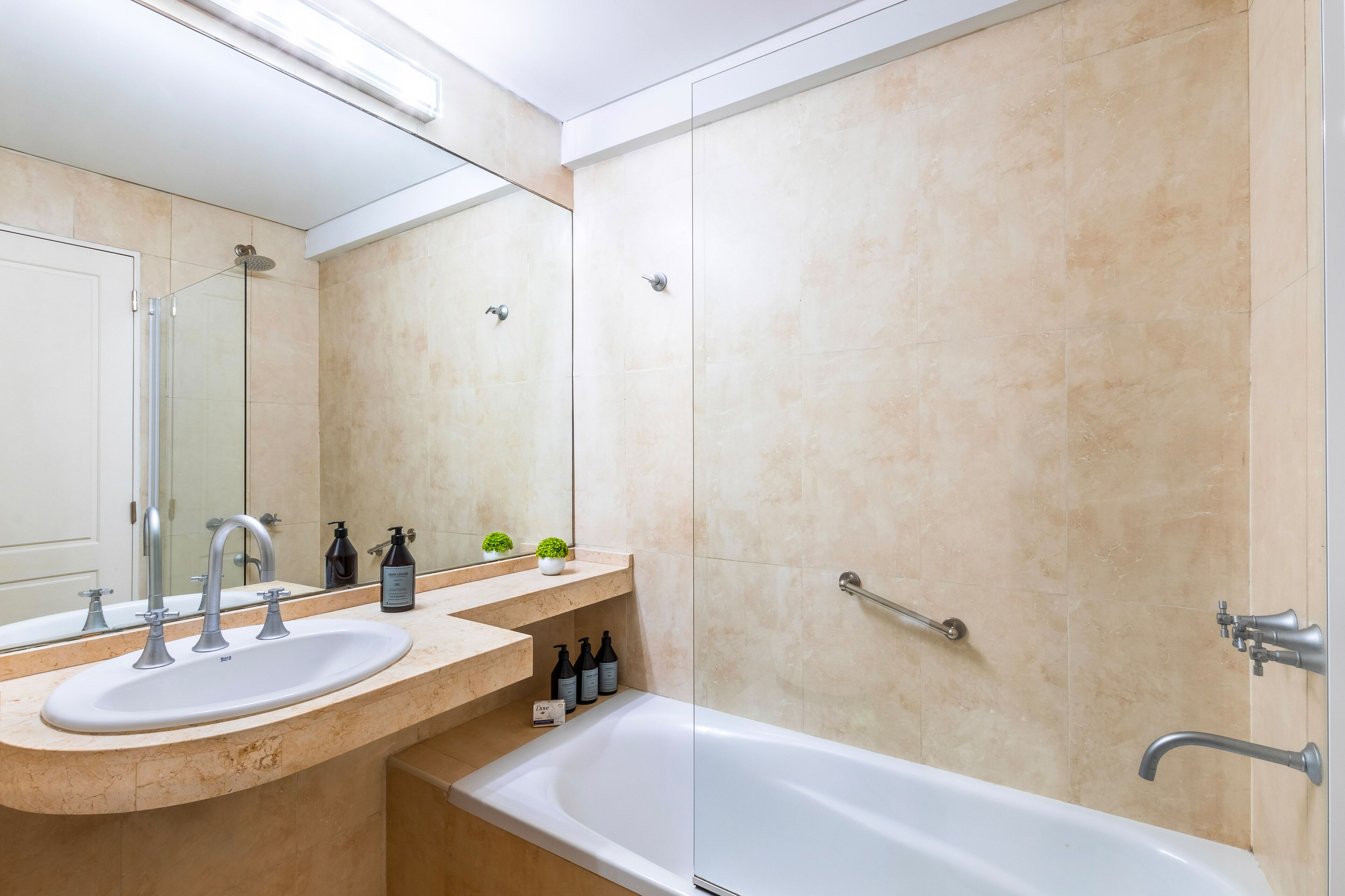 A modern bathroom with a sink, mirror, and bathtub.