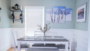 A dining area with a wooden table, white chairs, and a bench. There are framed pictures on the wall and a window with blinds. - Riverside Getaway! Minutes to Downtown Woodstock (Woodstock)